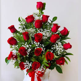 Red roses arranged in a white basket with baby's breath
