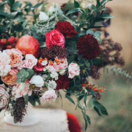 Bouquet of pink and burgundy flowers with greenery in a white vase