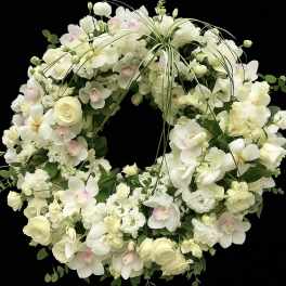 Round wreath of white and ivory flowers with soft pink-tinted orchids on a black background