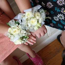 Two white floral wrist corsages with ribbon and lace accents