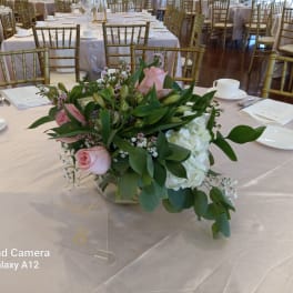 Pink roses and white hydrangeas in a low glass centerpiece on a banquet table