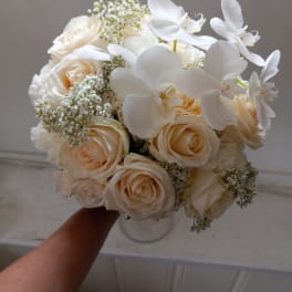 Bouquet of cream roses and white orchids in a clear vase
