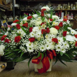 Large red and white floral arrangement in a basket with a red ribbon