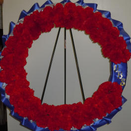 Red floral wreath on a stand with blue ribbon trim