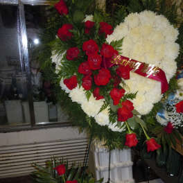 Standing floral tribute with red roses and white chrysanthemums on a frame