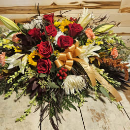 Large bouquet of red roses, white lilies, and sunflowers with a gold ribbon