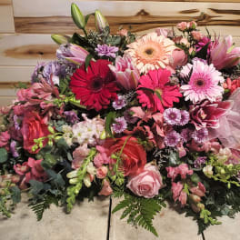 Large pink and red floral arrangement with a sheer ribbon