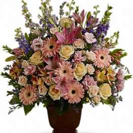 Large mixed flower arrangement in a dark urn vase