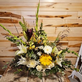 Tall mixed floral arrangement with white lilies, yellow gerbera daisies, and greenery