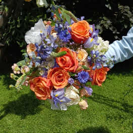 Handheld bouquet of orange roses and blue-purple flowers