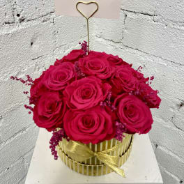 Hot pink roses in a gold striped box with a heart pick