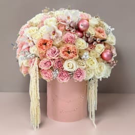 Pink and white rose arrangement in a blush cylindrical box with hanging strands