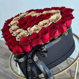 Heart-shaped box of red and gold roses with a black ribbon