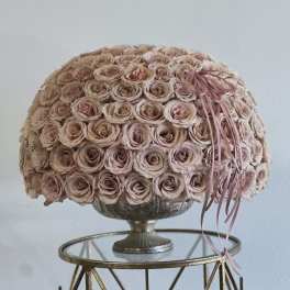Round bouquet of pale pink roses in a pedestal vase with ribbon