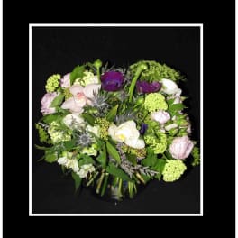 Mixed bouquet of purple, white, and green flowers in a glass vase
