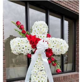 White floral cross with red roses and a white ribbon