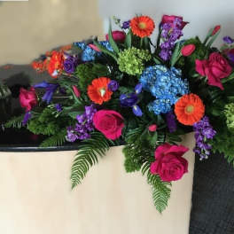 Colorful floral arrangement in a cream vase with roses and daisies