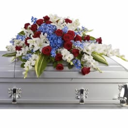 Red, white, and blue casket spray with roses, lilies, and delphinium on a silver casket