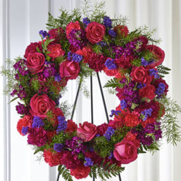Bright pink and purple standing wreath of roses and carnations on a black metal easel