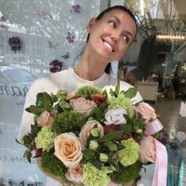 Woman holding a pink box of pastel roses and green carnations