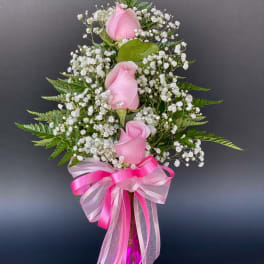 Pink roses with baby's breath in a pink glass vase