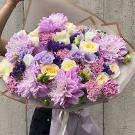 Large bouquet of lavender, cream, and yellow flowers wrapped in paper