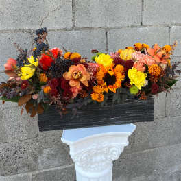 Autumn floral arrangement with sunflowers, mums, and berries in a black container