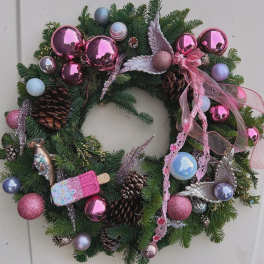 Christmas wreath with pink ornaments, pinecones, and ribbon