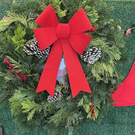 Christmas wreath with a large red bow, pinecones, and evergreen branches