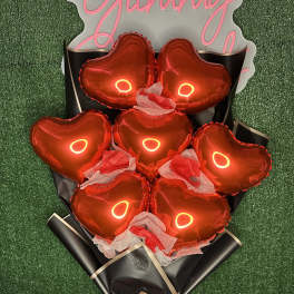 Bouquet of red heart-shaped balloons wrapped in black paper with a red ribbon