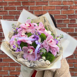 Large bouquet of pink orchids and purple flowers wrapped in paper
