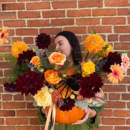 Woman holding a pumpkin filled with colorful flowers