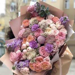 Large bouquet of pink, peach, and lavender flowers wrapped in blush paper