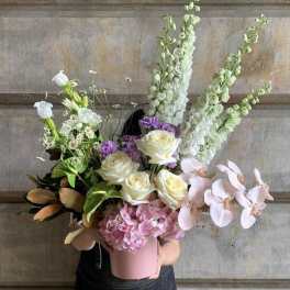 Mixed bouquet in a pink hatbox with white, pink, and purple flowers