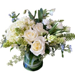 White roses and hydrangeas in a glass vase with blue accents