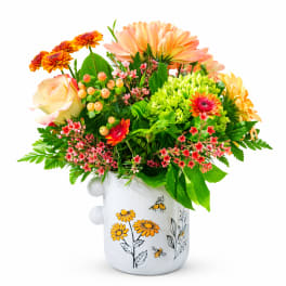 Mixed bouquet in a white ceramic mug with peach, yellow, and pink flowers