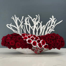 Low arrangement of red roses with white accents in a shallow bowl