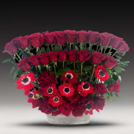Red roses and anemones arranged in a clear vase