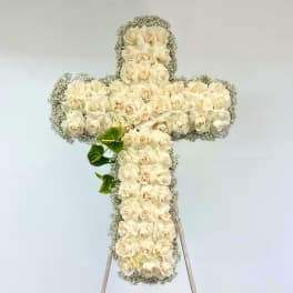White rose cross-shaped floral arrangement on a stand