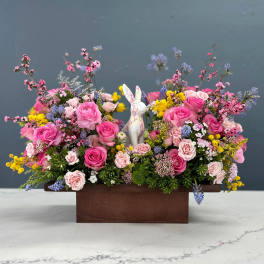 Pink rose arrangement in a wooden box with a ceramic rabbit figurine