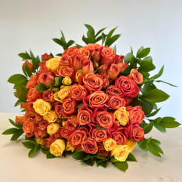 Bouquet of orange, red, and yellow roses with green foliage