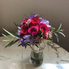 Bouquet of red roses and purple flowers in a glass vase