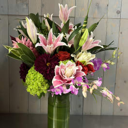 Mixed bouquet of lilies, orchids, roses, and hydrangeas in a glass vase