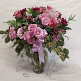 Pink rose bouquet in a glass vase with a lavender ribbon