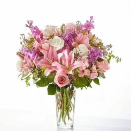 Pink and white bouquet of lilies and roses in a clear glass vase