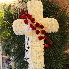 White floral cross with red roses and a white ribbon