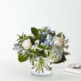 White roses and blue flowers in a clear glass vase