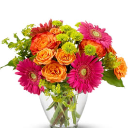 Bouquet of orange roses and pink gerbera daisies in a clear glass vase