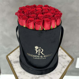 Red roses arranged in a black round hat box
