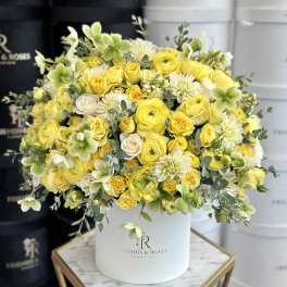 Yellow and white flower arrangement in a white hat box